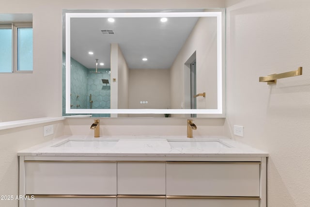 bathroom with double vanity, a shower stall, visible vents, and a sink