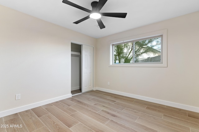 unfurnished bedroom featuring baseboards, ceiling fan, a closet, and wood tiled floor