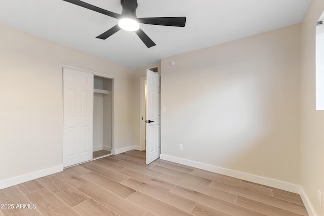 unfurnished bedroom with wood finish floors, a closet, a ceiling fan, and baseboards