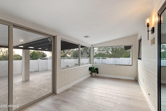 unfurnished sunroom with lofted ceiling and visible vents