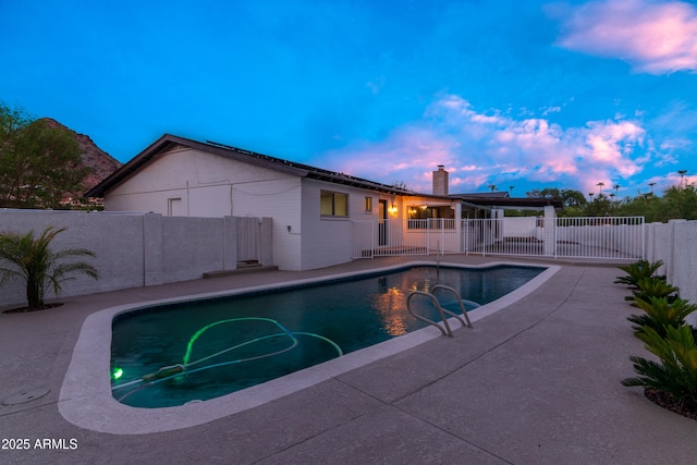 pool at dusk featuring a fenced in pool, a patio area, and a fenced backyard