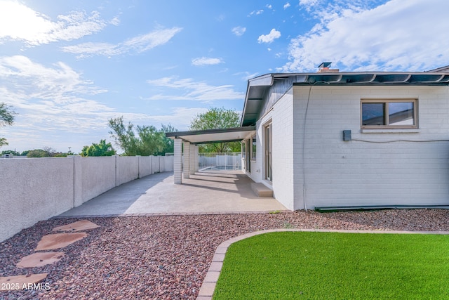 view of side of home with a fenced backyard, concrete block siding, a lawn, and a patio