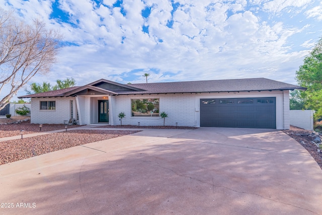 view of front of house with a garage, concrete driveway, and brick siding