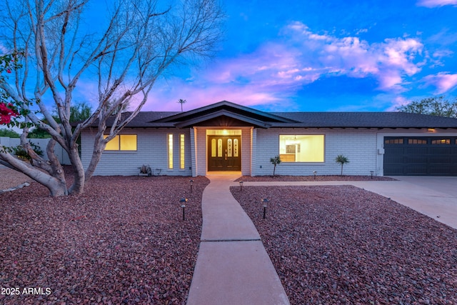 view of front facade with a garage, french doors, brick siding, and driveway