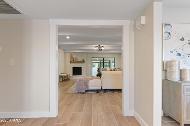 living room with light wood finished floors, visible vents, and baseboards