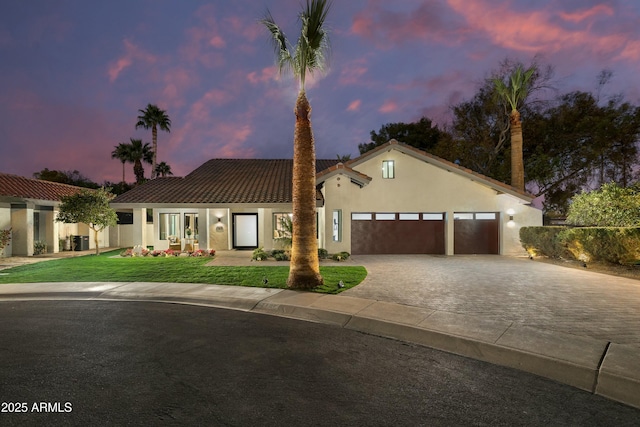 mediterranean / spanish home featuring a garage and a yard