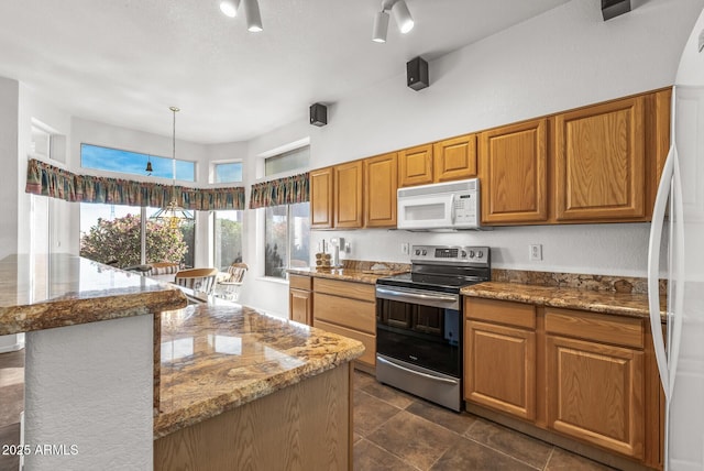 kitchen featuring decorative light fixtures, a center island, electric range, fridge, and light stone countertops