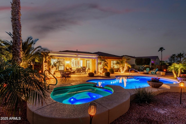 view of swimming pool with a patio area, a pool with connected hot tub, a ceiling fan, and outdoor dining space