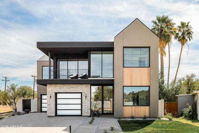 contemporary house featuring driveway, a front yard, fence, and a balcony