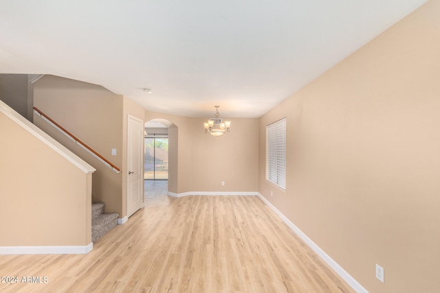 unfurnished room with light wood-type flooring and a chandelier