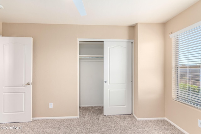 unfurnished bedroom with ceiling fan, light colored carpet, and a closet