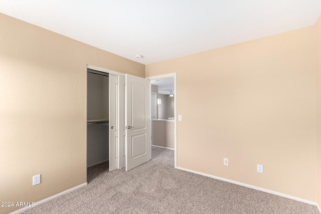 unfurnished bedroom featuring light carpet and a closet