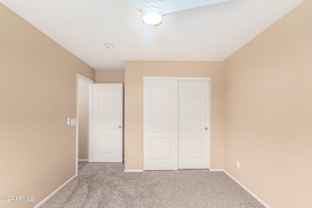 unfurnished bedroom with ceiling fan, light colored carpet, and a closet