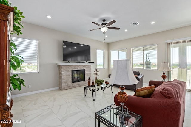 living room with ceiling fan, light tile floors, and a stone fireplace