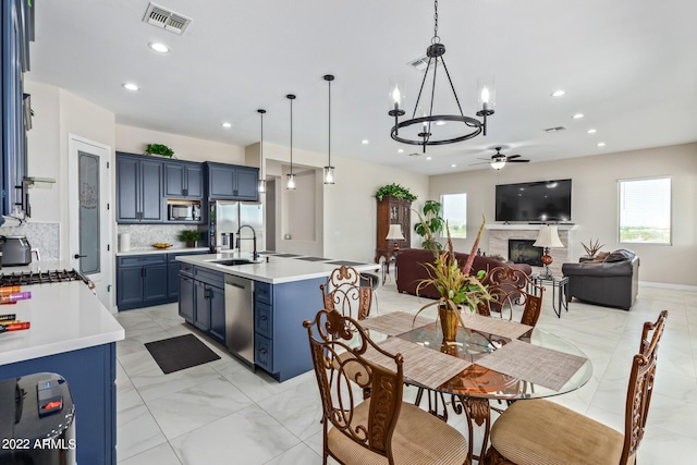 kitchen with pendant lighting, light tile flooring, ceiling fan with notable chandelier, backsplash, and blue cabinetry