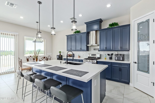 kitchen with blue cabinets, sink, stainless steel range with gas stovetop, and a kitchen island with sink