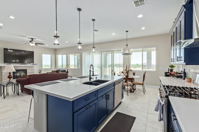 kitchen featuring plenty of natural light, wall chimney range hood, a kitchen island with sink, and sink