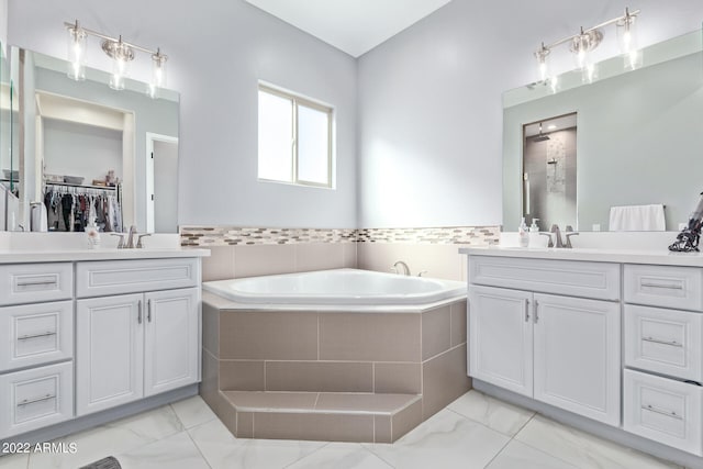 bathroom with a relaxing tiled bath, dual vanity, and tile flooring