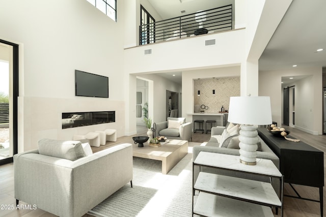 2315 E Mine Creek Rd, Phoenix, AZ 85024 - living area featuring a glass covered fireplace, wood finished floors, baseboards, a high ceiling, and recessed lighting