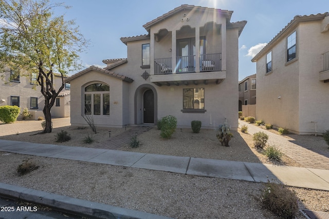 mediterranean / spanish-style home with a tiled roof, a balcony, and stucco siding