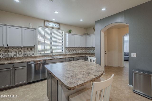 kitchen with a sink, arched walkways, dishwasher, and gray cabinetry