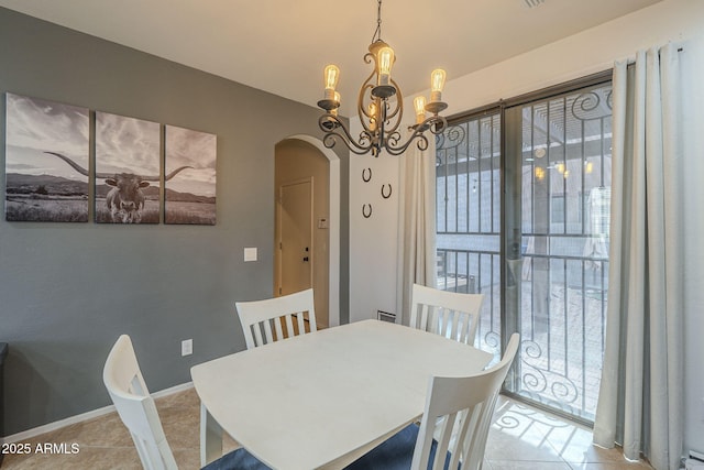 dining room with arched walkways, tile patterned flooring, a chandelier, and baseboards