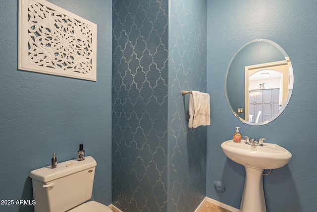 half bath featuring a textured wall and toilet