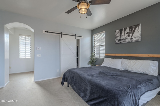 bedroom featuring light carpet, a barn door, multiple windows, and baseboards