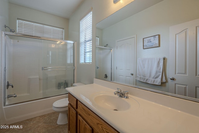 full bath with combined bath / shower with glass door, vanity, toilet, and tile patterned floors