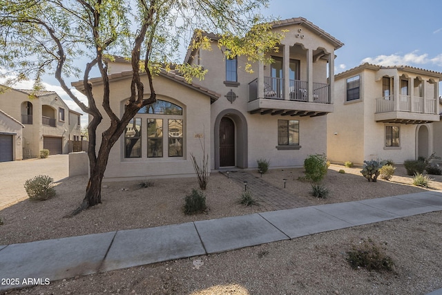 mediterranean / spanish home featuring a tiled roof, a balcony, and stucco siding