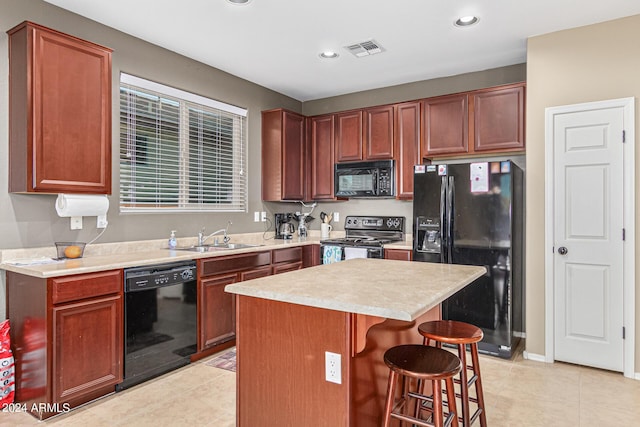 kitchen with a center island, black appliances, sink, light tile patterned floors, and a breakfast bar area