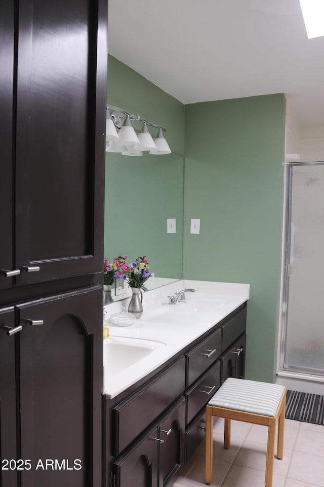 full bath with tile patterned flooring, a sink, double vanity, and a stall shower