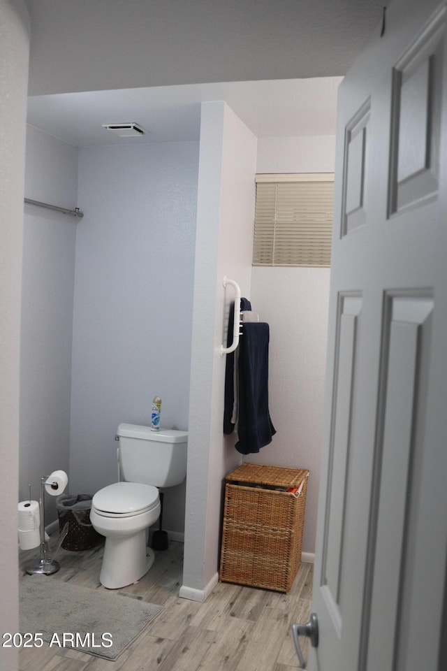bathroom with wood finished floors, visible vents, toilet, and baseboards