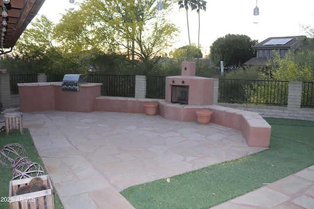 view of patio featuring exterior kitchen, exterior fireplace, a grill, and fence