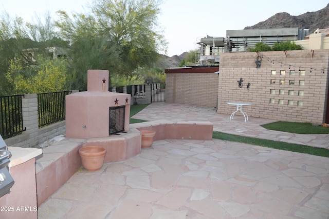 view of patio / terrace with exterior fireplace and fence