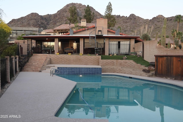 back of house with a fenced in pool, a mountain view, a chimney, fence, and a patio