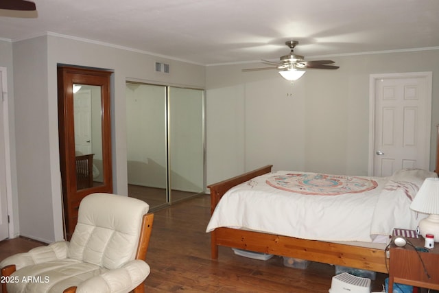 bedroom featuring a closet, wood finished floors, visible vents, and crown molding