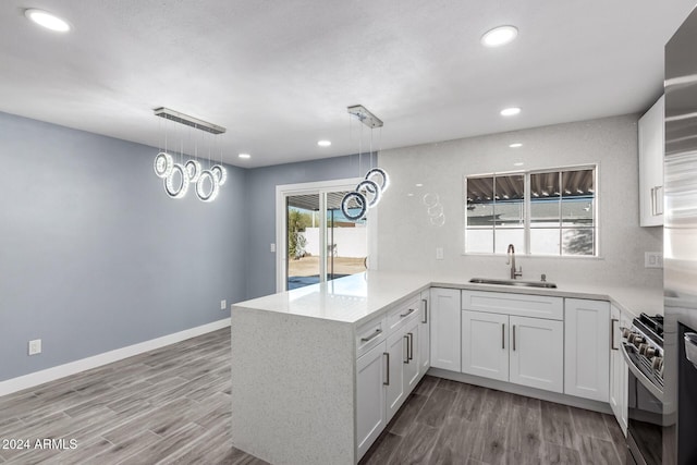 kitchen featuring white cabinets, light wood-type flooring, kitchen peninsula, and hanging light fixtures