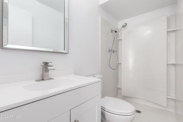 bathroom featuring a tile shower, vanity, and toilet