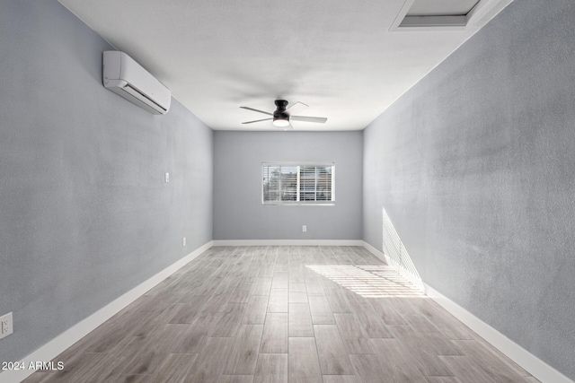 spare room featuring light hardwood / wood-style flooring, a wall unit AC, and ceiling fan