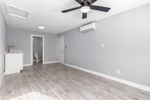 spare room with ceiling fan, light hardwood / wood-style floors, a wall mounted AC, and sink