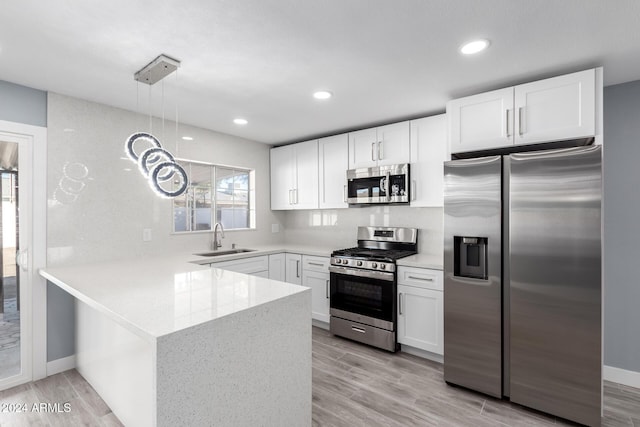 kitchen with pendant lighting, sink, light wood-type flooring, appliances with stainless steel finishes, and white cabinetry