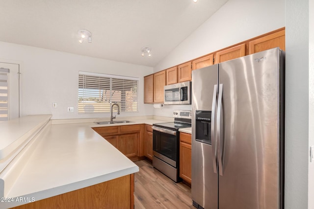 kitchen with sink, kitchen peninsula, lofted ceiling, appliances with stainless steel finishes, and light wood-type flooring