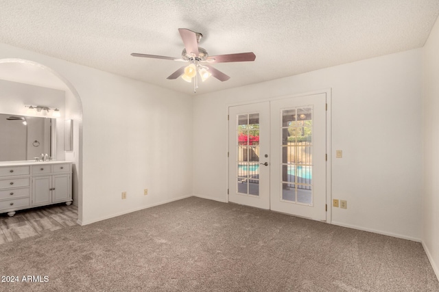 unfurnished bedroom featuring access to exterior, french doors, sink, carpet floors, and a textured ceiling