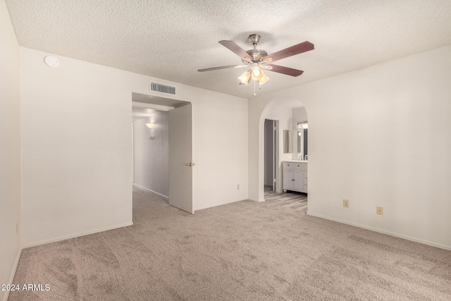 empty room with light carpet, a textured ceiling, and ceiling fan