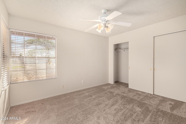 unfurnished bedroom with ceiling fan, carpet floors, a textured ceiling, and a closet