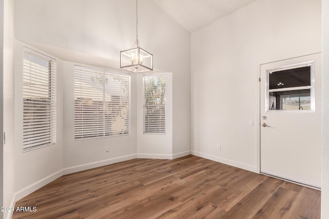 unfurnished dining area with a chandelier, lofted ceiling, and dark wood-type flooring