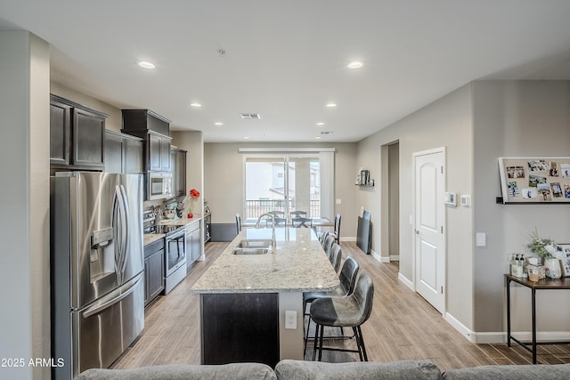 kitchen with sink, light hardwood / wood-style flooring, stainless steel appliances, and an island with sink