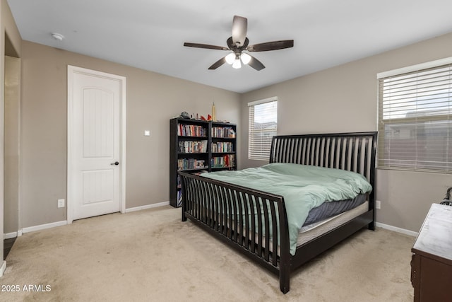 bedroom with light colored carpet, a ceiling fan, and baseboards