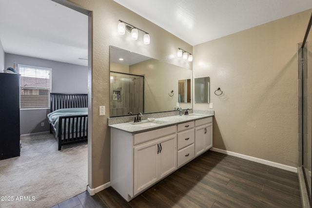 bathroom with double vanity, wood finished floors, baseboards, and a sink